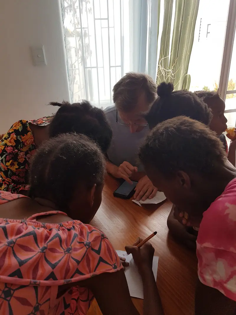 Kinder und das Team von ubuntu beugen sich zusammen an einem Tisch und schreiben ein Rezept auf.